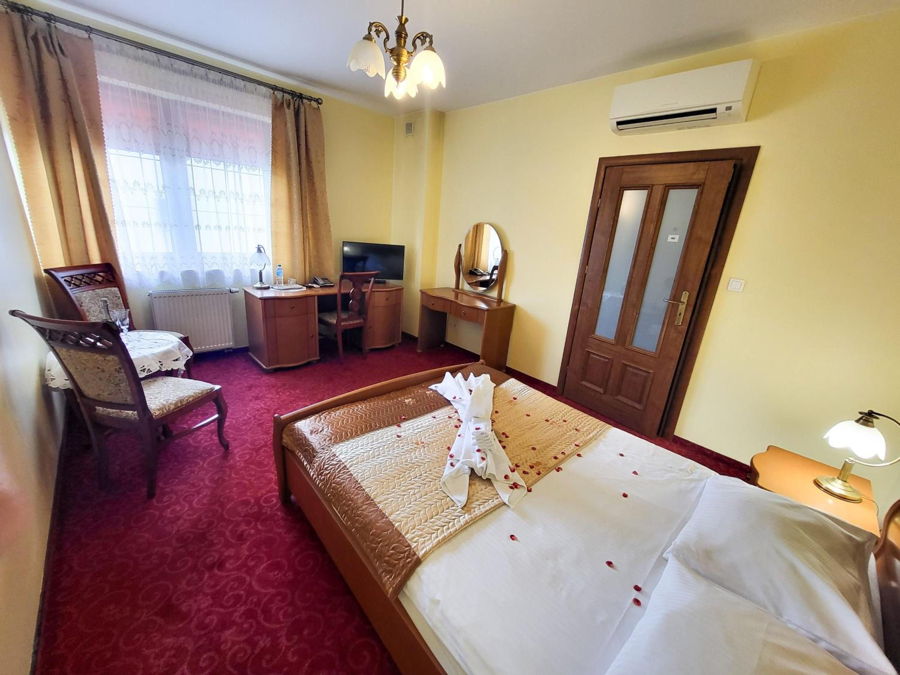 Ein Hotelzimmer mit einem Bett, einem Schreibtisch, einem Sessel, einem Fernseher und einer Klimaanlage.