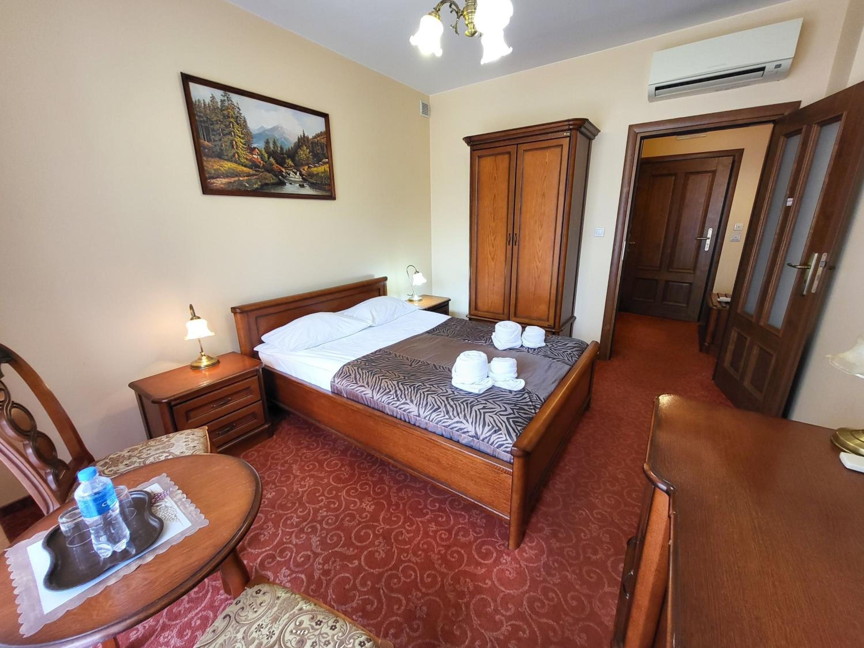 Habitació d'hotel amb un llit, escriptori, cadira, armari i aire condicionat.