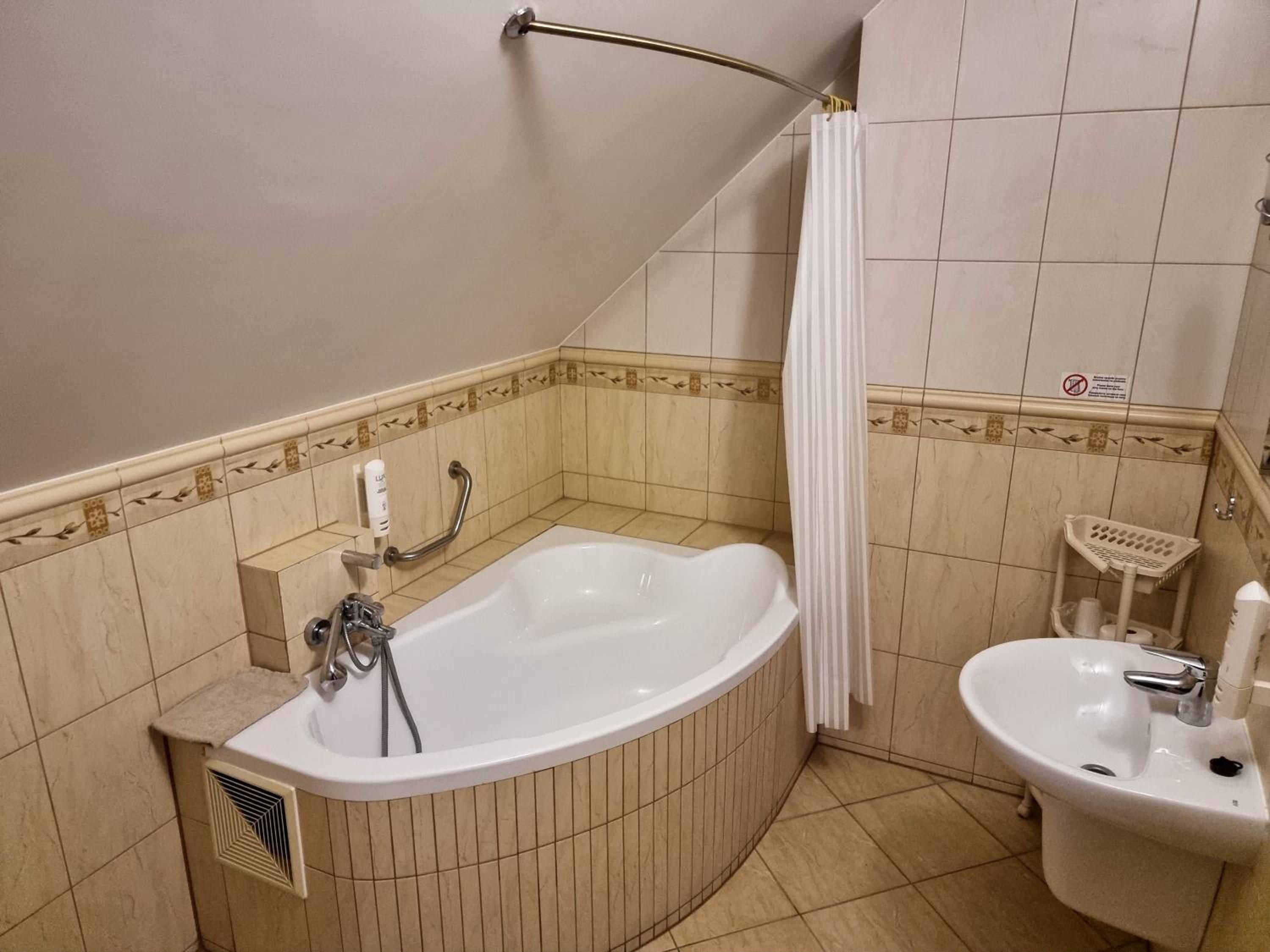 A bathroom with a bathtub, a sink, and a shower curtain.