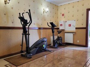 A fitness room with two stationary bikes and a wall-mounted exercise machine.