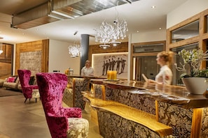 Un hall de hotel con mostrador de recepción, asientos cómodos y un ventanal grande.