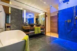 Un baño moderno con una bañera independiente, un espejo grande y una ducha a pie.
