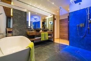 Un baño moderno con una bañera independiente, un espejo grande y una ducha a pie.