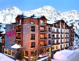 Un hotel de varios pisos con un letrero llamativo, amplias ventanas y montañas al fondo.