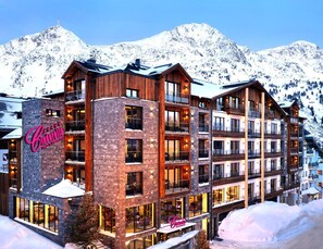 Un hotel de varios pisos con un letrero llamativo, amplias ventanas y montañas al fondo.