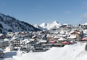 Un pueblo cubierto de nieve en la montaña, con edificios y una pista de esquí.