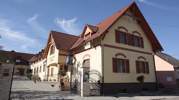 A traditional European-style building with a pitched roof, multiple windows with shutters, and a gated entrance.