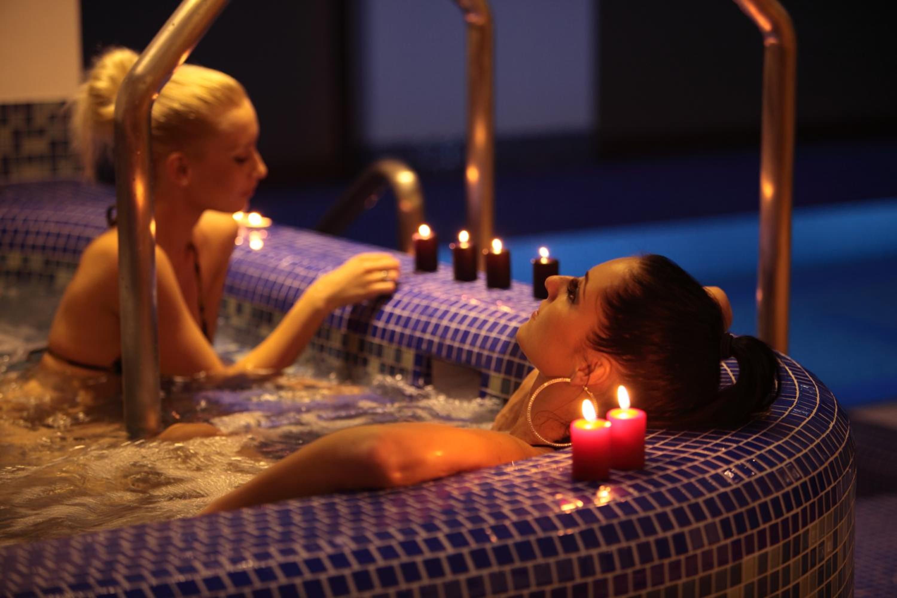Två personer i ett bubbelbad med tända ljus.