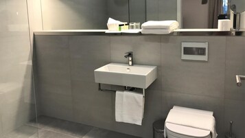 Un baño moderno con un lavamanos blanco, un espejo y un inodoro.