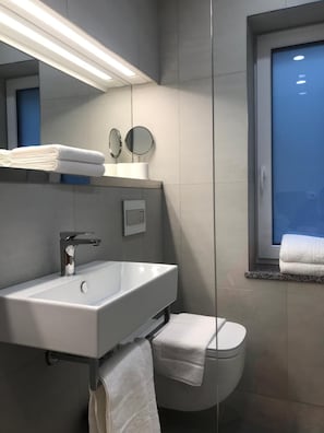 Un baño moderno con un lavabo blanco, un espejo y un inodoro.