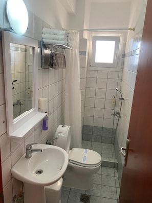 A compact bathroom with a sink, toilet, and shower area. - Korali Hotel (Katerini)