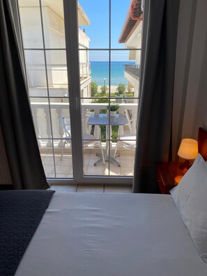 A hotel room with a balcony, a bed, a table, and a lamp. - Korali Hotel (Katerini)