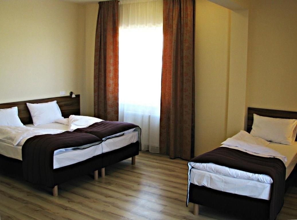 A hotel room with two beds, wooden flooring, and a window with curtains.