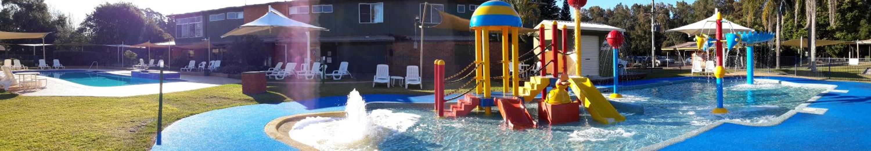 A swimming pool with a water play area and lounge chairs.