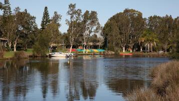 A calm lake with boats, trees, and a small building with a roof.