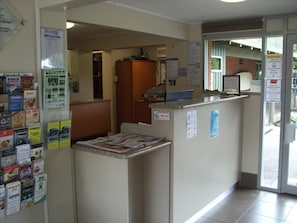Zona de recepción con mostrador, carteles informativos y vistas al exterior.