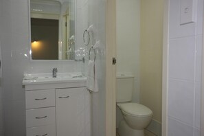 Un baño con lavamanos, espejo y retrete blancos.