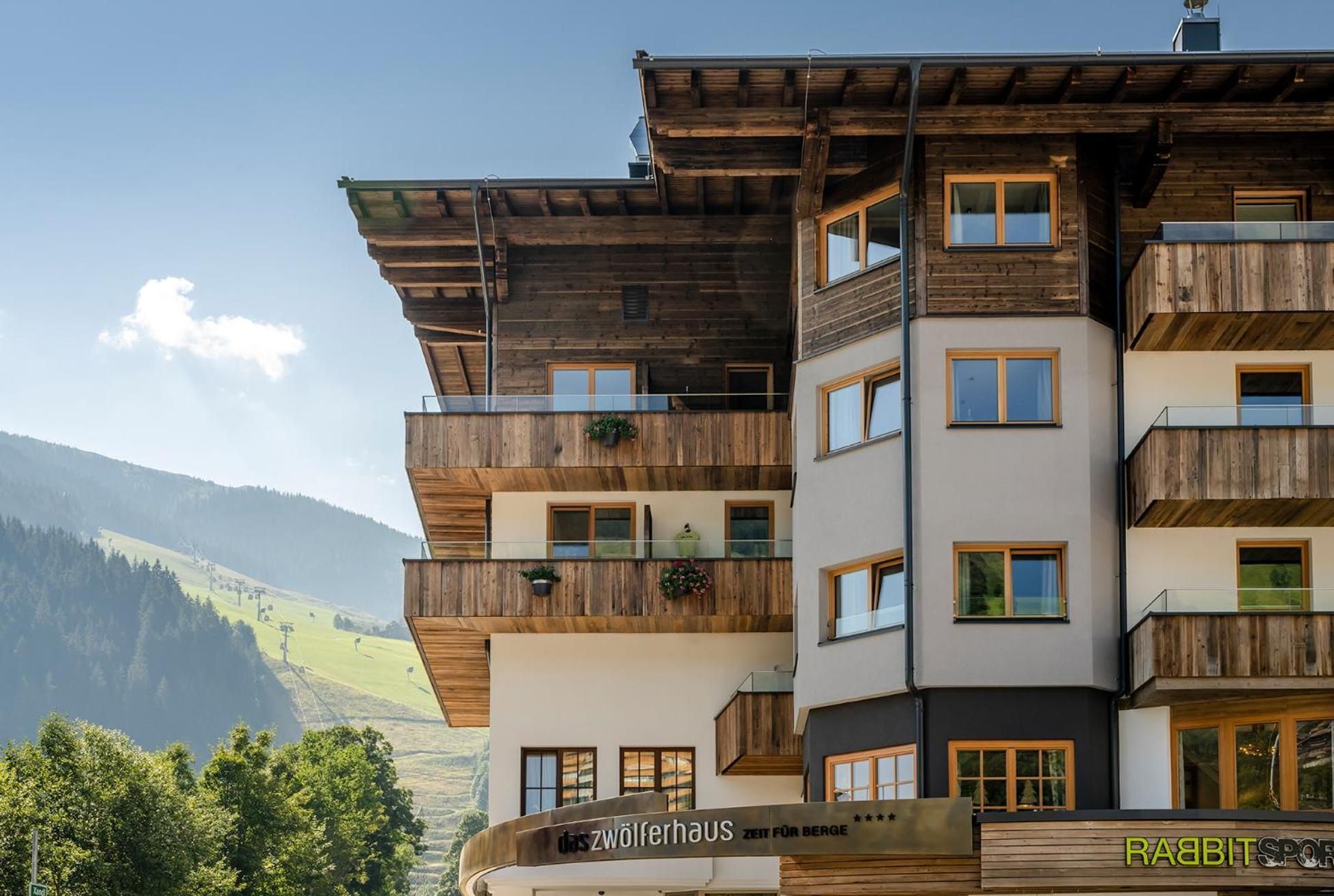 A multi-story hotel with wooden balconies and a view of the mountains.