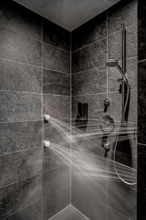 Una doccia moderna con soffione a pioggia, doccetta manuale e massaggiatore da bagno.