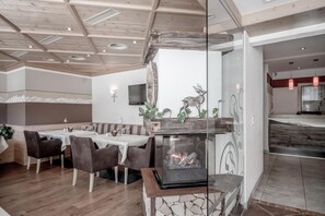 Un'area pranzo moderna con camino, soffitto in legno e vista sulla cucina.