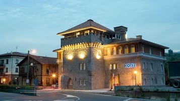 A hotel with a stone facade, a tower, and a sign indicating it is a hotel.