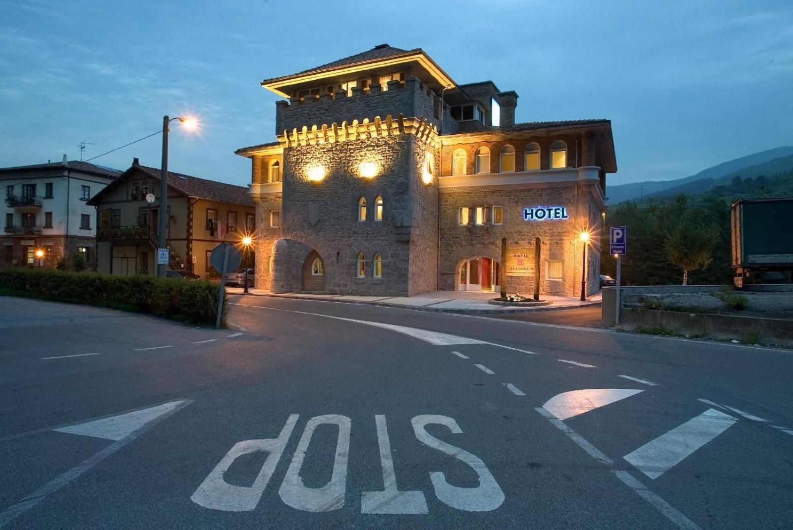 A hotel with a stone facade, a stop sign in the foreground, and a parking sign.