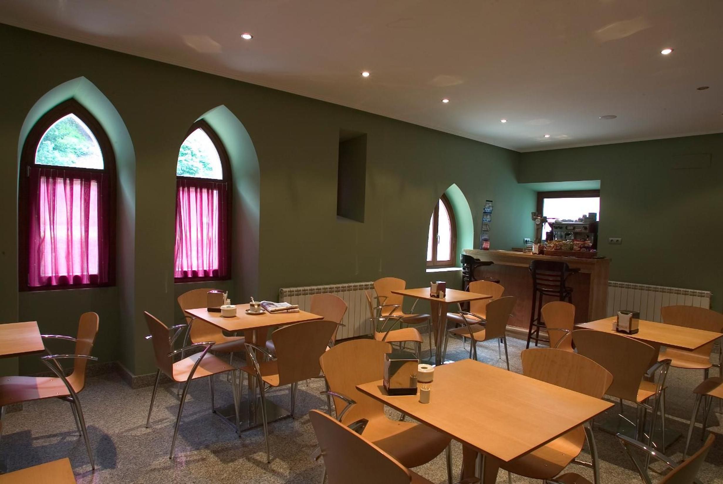 A dining area with tables and chairs, a bar area, and arched windows with curtains.