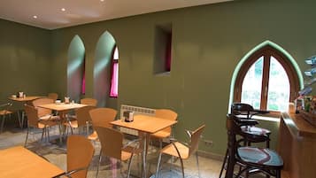 A dining area with tables and chairs, a counter with snacks, and a window with a view.
