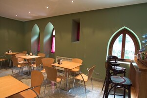 Un comedor con mesas y sillas, una barra con aperitivos, y un ventanal con vistas.