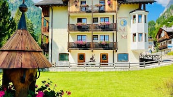 Ein mehrstöckiges Gebäude mit Balkonen, einem Schild mit der Aufschrift 'Apartments Sol & Neef' und einem Berg im Hintergrund.