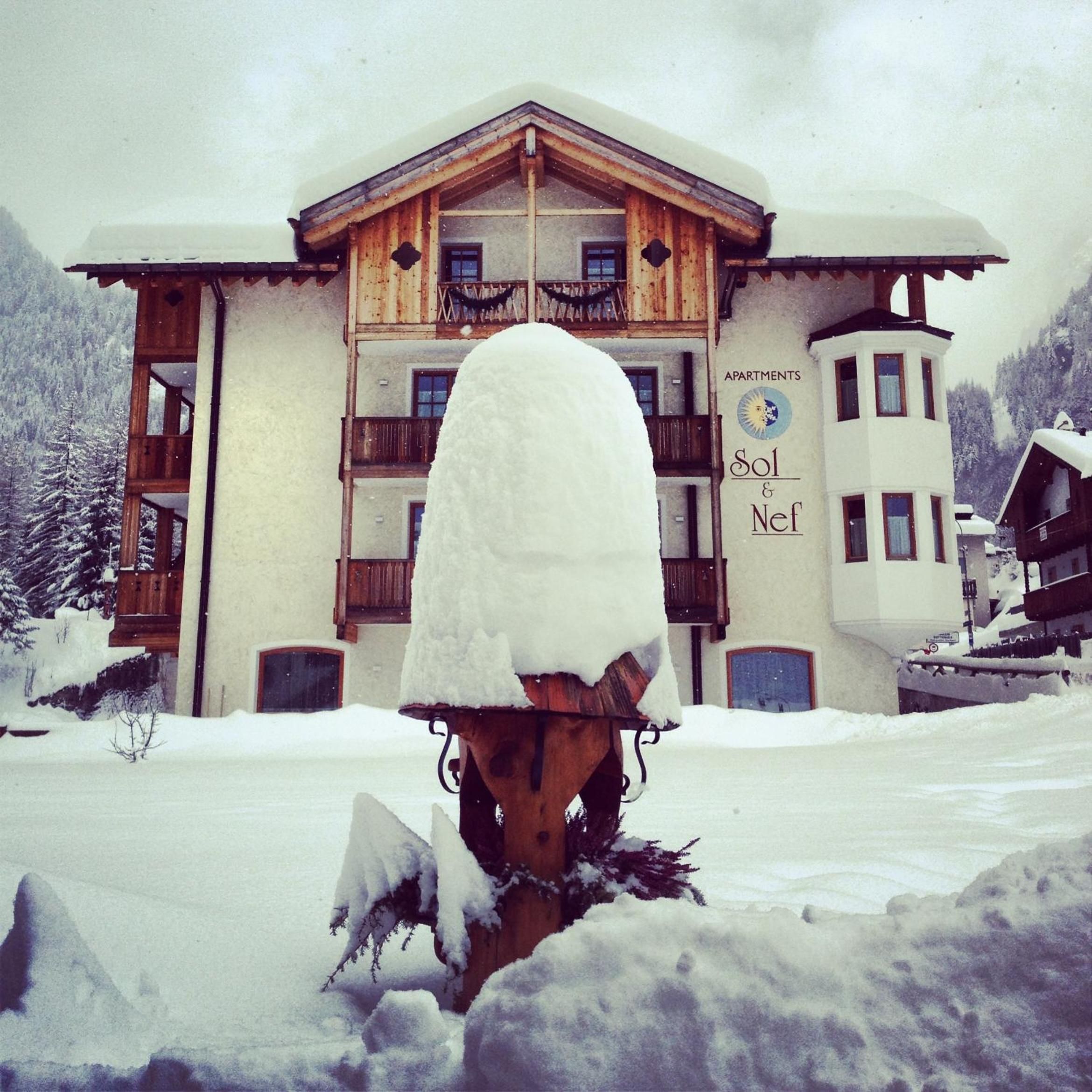 A snow-covered building with a balcony and a sign that reads 'APARTMENTS Sol & Nef.'