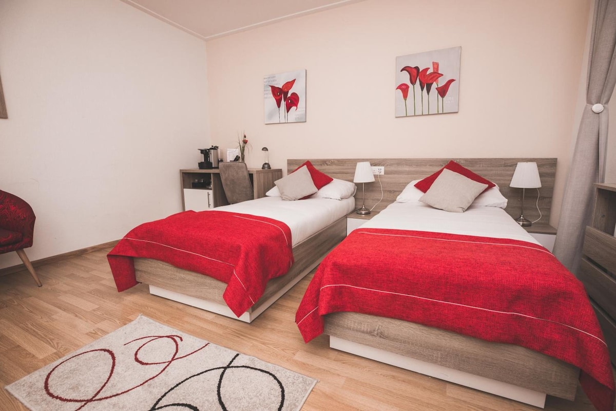 Una habitación de hotel con dos camas, un escritorio y una mesita de noche.