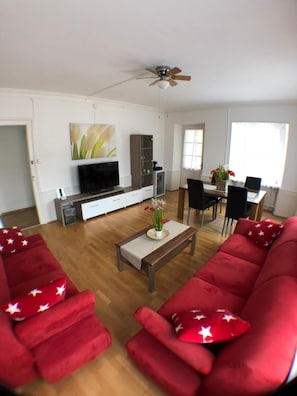 Una sala de estar con un sofá rojo, una mesa de centro y un televisor.