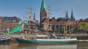 A historic ship docked near a waterfront with a church in the background. - Alexander Von Humboldt Das Schiff (Bremen)