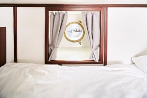 A hotel room with a bed, a wooden headboard, and a window with curtains. - Alexander Von Humboldt Das Schiff (Bremen)