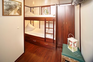 A bunk bed with a wooden frame, a small bedside table with a lantern, and a wardrobe with a mirror. - Alexander Von Humboldt Das Schiff (Bremen)