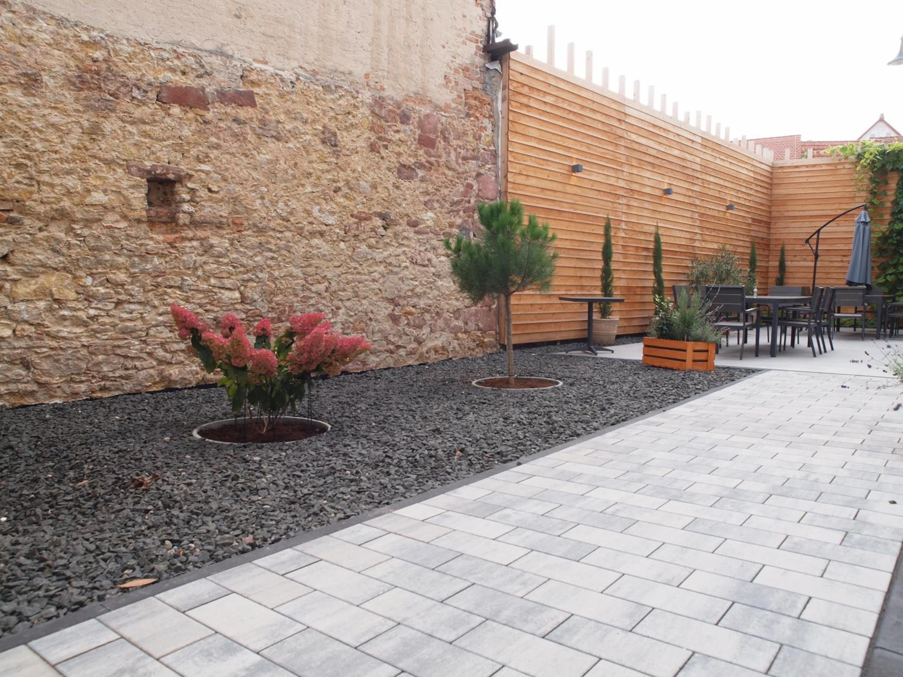 A courtyard with a stone wall, wooden fence, and outdoor seating area.