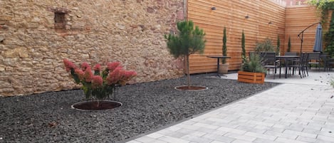 A courtyard with a stone wall, wooden fence, and outdoor seating area.
