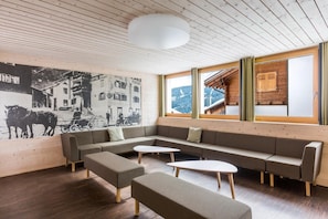 Un interior moderno con techo de madera, un mural grande en la pared, un conjunto de sofás y vistas a través de las ventanas.