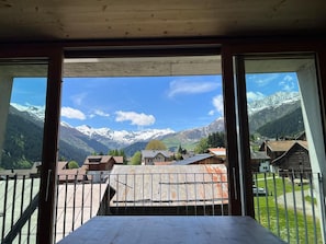 Una habitación con vistas a montañas nevadas, un balcón y una mesa.