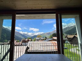 Una habitación con vistas a montañas nevadas, un balcón y una mesa.