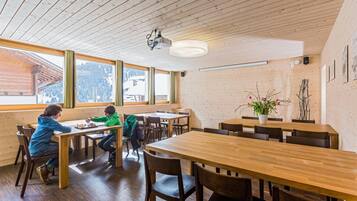 Un intérieur en bois avec des tables et des chaises, de grandes fenêtres et un ventilateur de plafond.