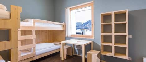 A bunk bed room with a desk and a window.
