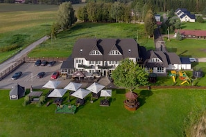A large building with a parking lot, outdoor seating area, and a playground. - Butenas Hotel Tyla (Biržai)