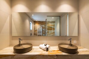 A bathroom with a large mirror, two vessel sinks, a towel, and a glass shower door. - El Greco (Igoumenitsa)