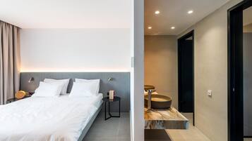 Une chambre d’hôtel moderne équipée d’un lit, de tables de chevet et d’une salle de bain avec un lavabo et un miroir.