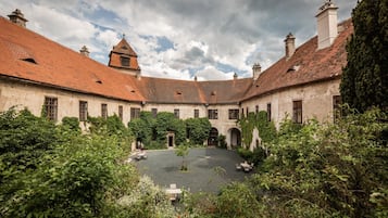 Ein Innenhof mit einem zentralen offenen Bereich, umgeben von Gebäuden mit roten Ziegeldächern und Bogenfenstern.