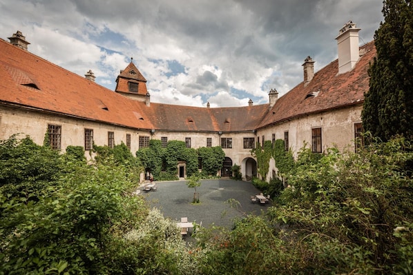 A courtyard with a central open space surrounded by buildings with red-tiled roofs and arched windows.