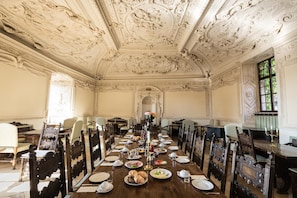 A formal dining room with ornate ceiling and classical furniture.