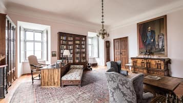 Ein geräumiges Zimmer mit einer großen Bücherwand, einem Sofa, einem Schreibtisch und einem Schachbrett.